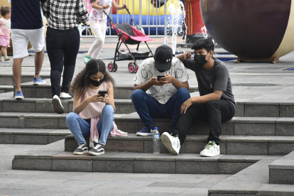 Jóvenes guayaquileños en el Malecón Simón Bolívar, todos mantienen fija la mirada en su dispositivo.