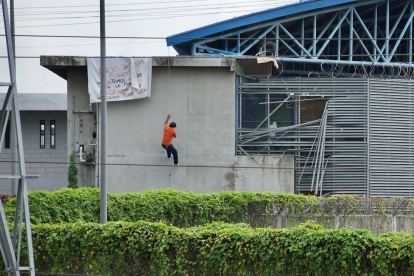 Fotografía de archivo, tomada el pasado 25 de febrero, en la que se registró a un preso al descender por una pared, durante un motín, en una cárcel de Guayaquil