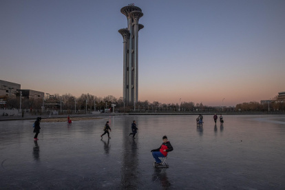 Varias personas patinan en el canal situado ante la Torre Olímpica cerca de las instalaciones deportivas para los Juegos Olímpicos de Invierno de Pekín 2022, en Pekín, China.