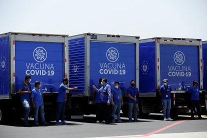 Vista de trabajadores de la salud junto a camiones refrigerantes que transportarán un lote de vacunas, en una fotografía de archivo.