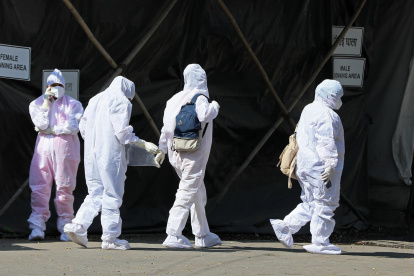 Health workers wearing personal protective equipment walk past a quarantine centre in Mumbai, India, 20 January 2022.