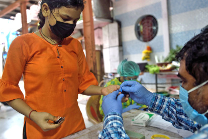 Un sanitario toma una muestra de sangre a una joven para detectar malaria y dengue en Mumbai / El País