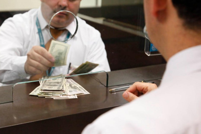 EMPLEADO O CAJERO DE BANCO CONTANDO DINERO EN LA VENTANILLA.