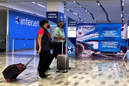 Espera. Dos personas pasan frente a un mostrador de Interjet en el aeropuerto de Ciudad de México. Miles llevan un año sin volar en esta aerolínea.