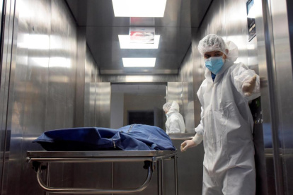 Personal de salud traslada a un paciente fallecido por la covid-19