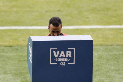 Wimar Roldán observa el VAR para cambiar la expulsión del arquero brasileño Alisson por una amonestación.
