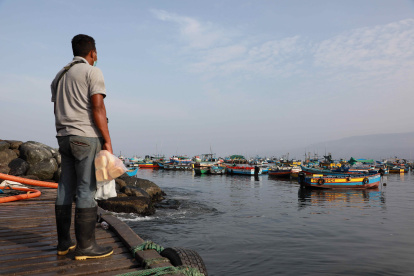 Un pescadores artesanales observa los botes en la bahía de Ancón, el 25 de enero de 2022 en Lima (Perú). Cada mañana, durante cientos de años, el pueblo pesquero de Ancón se ha llenado de embarcaciones, redes y peces, pero ahora solo luce la desesperación y el enfado de pescadores que casi lo han perdido todo tras el gran desastre ambiental causado por el derrame de petróleo en el norte de Lima. EFE/ Juan Ponce