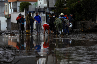 Vista de personas mientras ayudan en la labor de limpieza sobre el lodo ocasionado por las lluvias del día anterior, que afectó algunos barrios del oeste de la capital ecuatoriana, este 31 de enero de 2022.