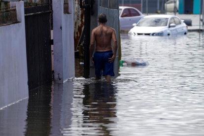Un hombre camina por una calle inundada debido a las intensas lluvias registradas el pasado fin de semana, hoy, en Cataño (Puerto Rico).