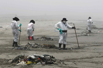 Personal de limpieza limpia y recoge basura, hoy en la playa Cavero en el distrito de Ventanilla en Lima (Perú).