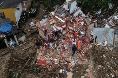 Fotografía tomada con un drone que muestra a dos hombres junto a una vivienda destrozada en medio de la destrucción tras las fuertes lluvias del martes en el Morro de la Oficina, el 18 de febrero de 2022, en la ciudad de Petrópolis, estado de Rio de Janeiro (Brasil).