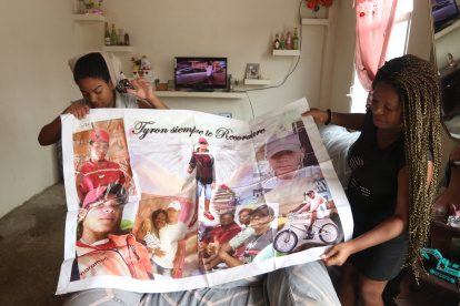 Mirtha Preciado junto a su otra hija exponiendo una gigantografía que guardan en casa para recordar a su familiar asesinado en la cárcel.