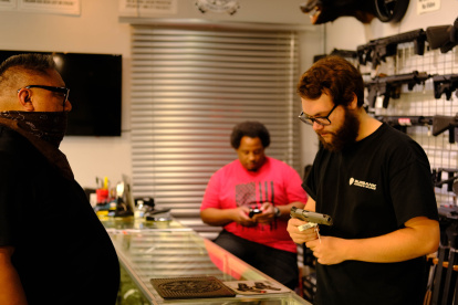 Un vendedor de la armería ‘Ammo and Guns’ muestra un revólver a un cliente.