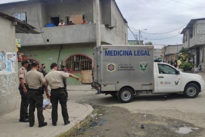 Policías rodean el cuerpo de la víctima que ha sido cubierto con una sábana.