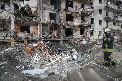 Un miembro de los servicios de emergencia evalúa los daños ocasionados por los bombardeos rusos sobre una zona residencial de Kiev