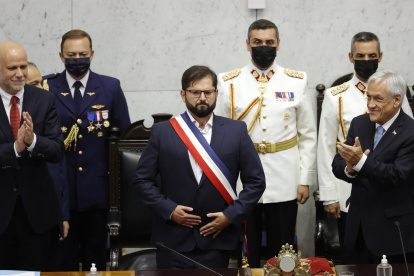 El presidente de Chile Gabriel Boric saluda a los asistentes al Congreso Nacional luego de recibir la banda presidencial del senador socialista Álvaro Elizalde (izq.), mientras el expresidente Sebastián Piñera (der.) aplaude hoy en Valparaiso (Chile).