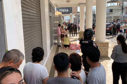 Familiares lloran junto al cadáver de la víctima, Cumandá Sánchez Benítez, luego de cubrirla con sábanas, en la entrada de su casa.
