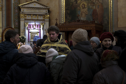 Uno de los sacerdotes de la Catedral Svyato-Uspensky, de la Iglesia Ortodoxa Ucraniana, ofrece una cruz a los fieles para que la besen durante el oficio. EFE/Manuel Bruque