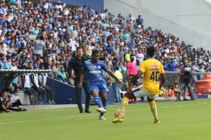 Romario Caicedo, jugador de Emelec, domina el balón mientras Ismael Rescalvo, entrenador azul, sigue la acción.