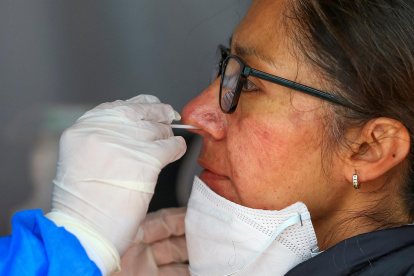 Fotografía de archivo de una mujer mientras se realiza una prueba PCR para detectar covid-19 en Quito (Ecuador).