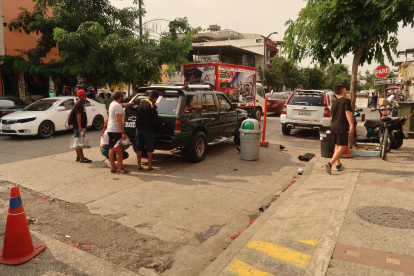 Las personas se aglomeran cerca de los vehículos en la calle Ayacucho