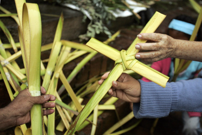Una mujer compra una cruz de palma de cera, en una fotografía de archivo