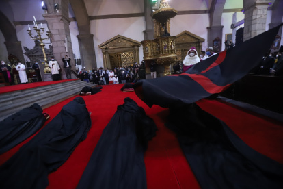 La bandera negra con una cruz roja es ondeada a los ocho canónigos postrados en el suelo.