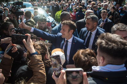 El presidente francés y candidato a la reelección Emmanuel Macron (c) saluda a la gente antes de acudir al colegio electoral en la segunda vuelta de las elecciones presidenciales francesas