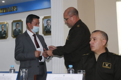 El Director del ISSPOL (d) entregando dos cheques al vocal principal del Consejo Directivo de la institución.