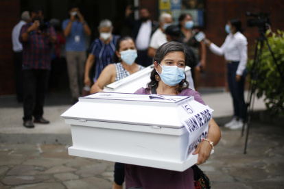 Una mujer lleva el ataúd que contiene las osamentas de un familiar, asesinado 1980 por el ejército salvadoreño, hoy, en San Salvador (El Salvador).