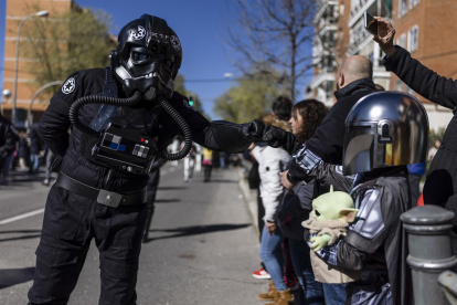 Un piloto del cuerpo imperial de cazas estelares TIE de la saga Star Wars (i) saluda a un pequeño mandaloriano (d) durante el desfile del Galaxy Day por una calle de Madrid.