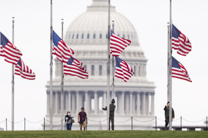 Funcionarios de Parques Nacionales ondean las banderas a media asta, este 12 de mayo de 2022 en Washington, para recordar a los fallecidos por covid-19, que superan el millón de personas en el país