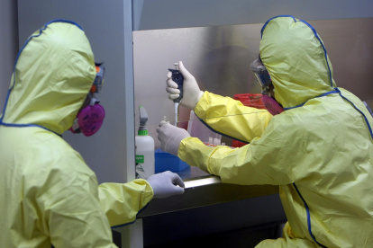 Imagen de archivo de dos médicos con trajes protectores.