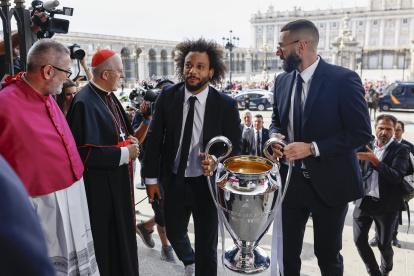 Los capitanes del Real Madrid Marcelo (i) y Karim Benzema (d) son recibidos por el arzobispo de Madrid, Carlos Osoro (2i), a su llegada a la Catedral de la Almudena, una de las paradas del recorrido realizado esta tarde por el equipo para celebrar su victoria en la final de la Liga de Campeones.
