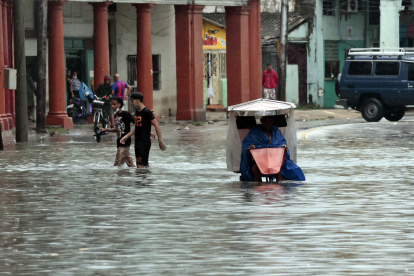 Varias personas caminan por una calle llena de agua, hoy en La Habana (Cuba).