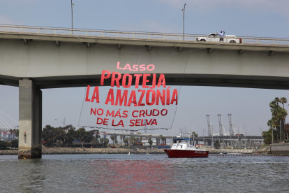 Fotografía cedida por Amazon Watch donde se aprecia a un hombre mientras observa una pancarta gigante