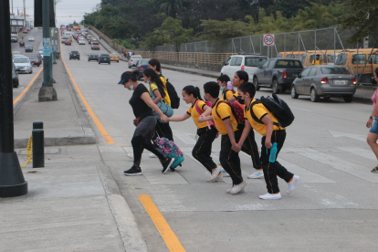 Padres y estudiantes del colegio Teniente Hugo Ortiz se lanzan a la avenida Teodoro Alvarado Oleas para ir de un carril a otro, sin tomar las debidas medidas.