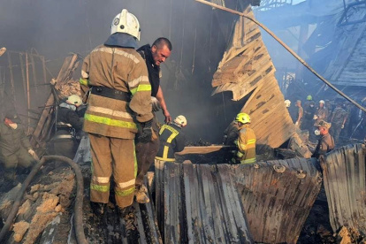 Unos bomberos levantan los escombros tratando de hallar alguna víctima de este atentado ruso a Ucrania./ EFE