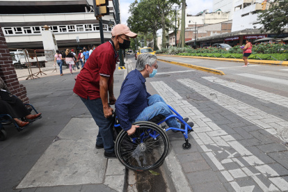 Aquiles Valarezo tuvo que pedir ayuda para cruzar de una acera a otra en el centro de la urbe, pues su silla de ruedas se quedó atorada en un hueco entre la rampa y la calzada.