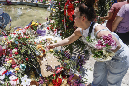 Fotografía de archivo, tomada el pasado 29 de mayo, en la que se registró a una mujer al hacer una ofrenda floral frente a la institución académica Robb Elementary School, en Uvalde (Texas, EE.UU.), luego de que un joven desadaptado asesinara a 19 niños y dos maestras e hiriera a otras 17 personas.