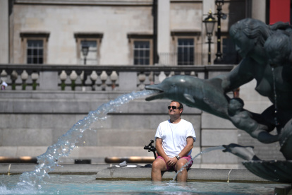 Un hombre descansa bajo una fuente en Trafalgar Square, en Londres. EFE/EPA/NEIL HALL
