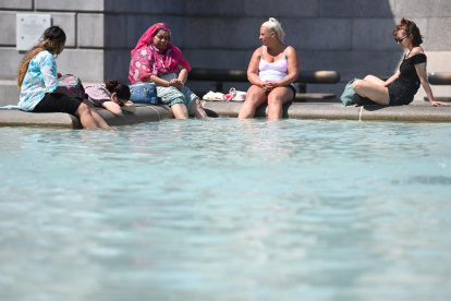 La gente se refresca en la fuente de Trafalgar Square, Londres.