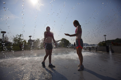 Personas se refrescan en una fuente ante las temperaturas registradas durante una ola de calor