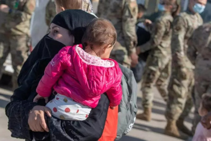 Una mujer afgana y su hijo acuden a un punto de recogida antes de partir hacia EE.UU.