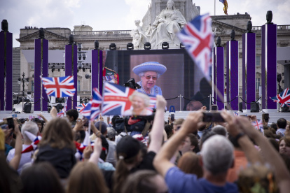 Londres. Gente en el centro comercial viendo a Su Majestad, la Reina en el balcón del Palacio de Buckingham mostrado en una pantalla grande durante las celebraciones del Jubileo de Platino de la Reina Isabel II, el 2 de junio de 2022.