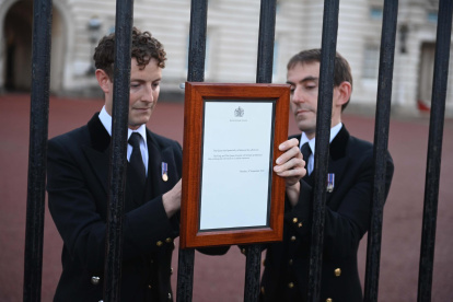 Miembros de la casa real británica publican el anuncio oficial de la muerte de la reina Isabel II en las puertas del Palacio de Buckingham este jueves.