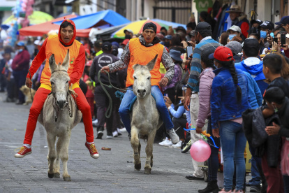Varias personas con sus burros participan en una carrera, hoy, en Salcedo (Ecuador).
