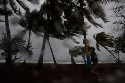 Una persona camina entre la lluvia y los fuertes vientos debido al paso de una tormenta por Puerto Rico, en una fotografía de archivo