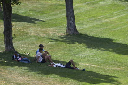 En la imagen de archivo, unos jóvenes se protegen a la sombra en un parque.