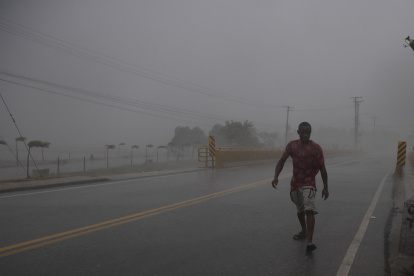 Un hombre camina en medio de una intensa ráfaga de viento y lluvia durante el paso del huracán Fiona, hoy, en Nagua (República Dominicana).